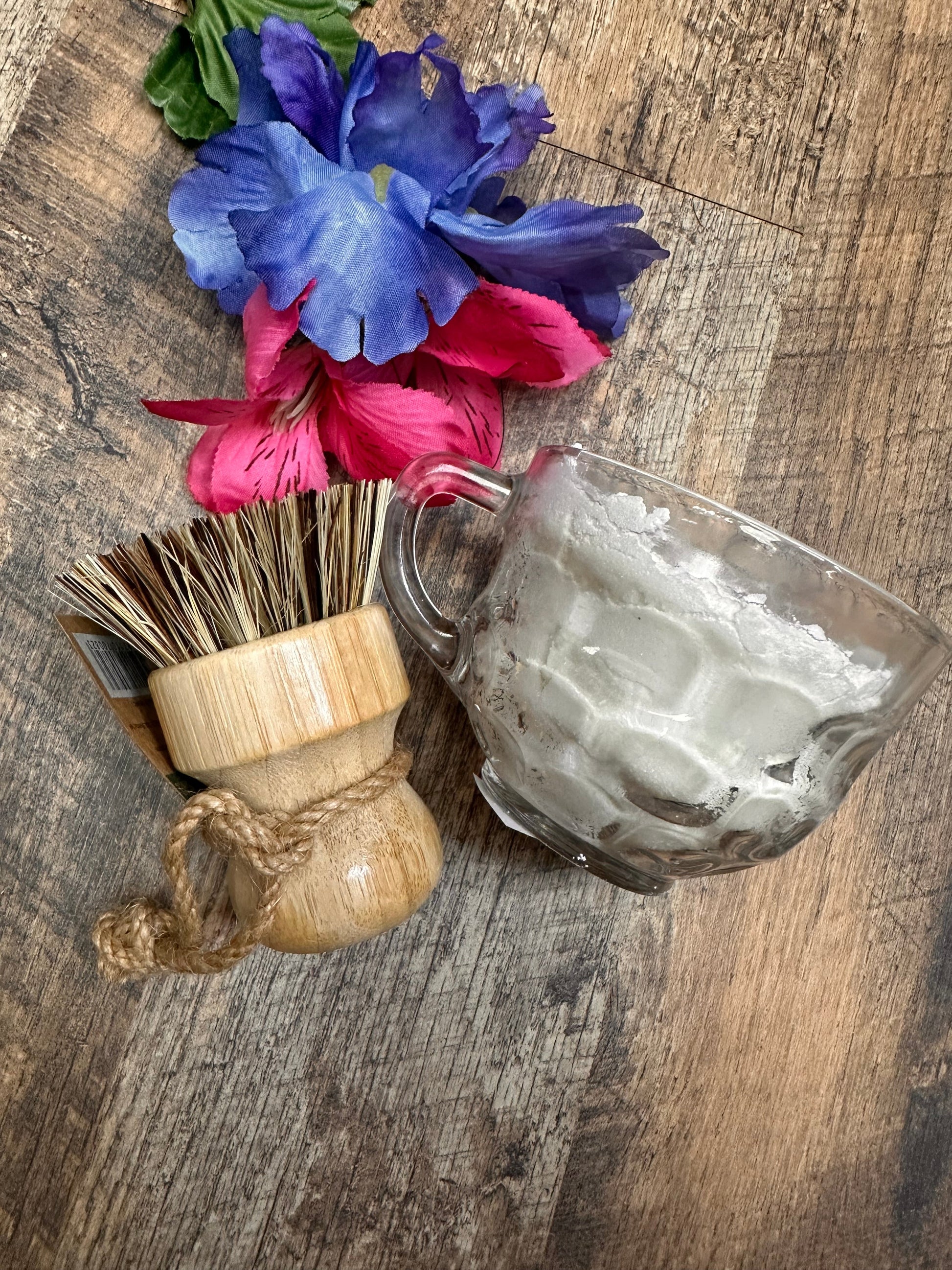Glass with a wooden brush and flowers on a wooden surface